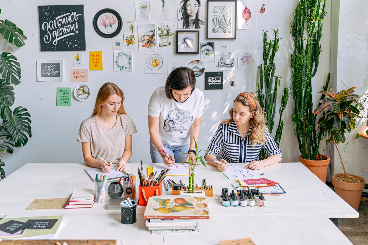 Art class scene with students and instructor working on creative projects in a bright, indoor studio.